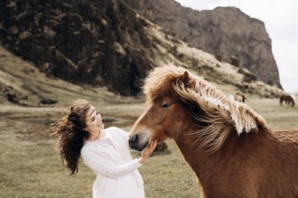 Destination Iceland wedding photo session with Icelandic horses. A bride in a white dress strokes a