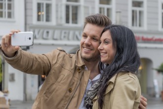 A young couple take a self-portrait with a mobile phone. Selfies are in. Austria