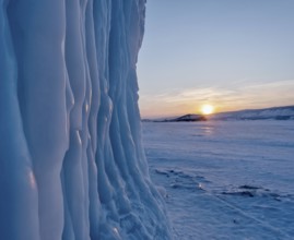 Icicles hang from the rocks on Lake Baikal at frosty winter sunset