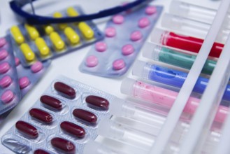 Various colorful pills and test tubes arranged on a lab table with glasses