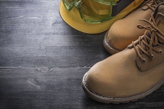 Protective spectacles building helmet safety boots on wooden board