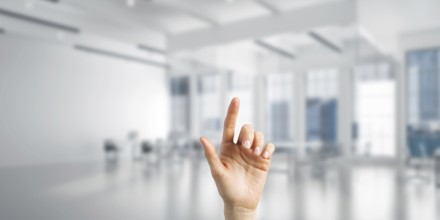 Close of woman hand touching screen with finger and office at background