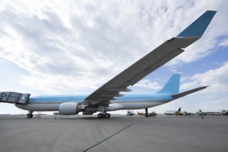 Large blue and white airplane stands at the airfield ready to depart, people&#39, s faces are
