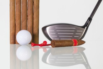 Golf driver and different cigars on a glass table