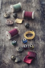 The spool of thread, beads and wire for needlework on wooden background
