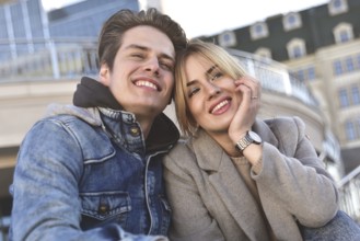Attractive young couple sitting on floor in urban street reading information on a tablet with a