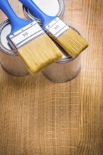 Vertical view organized copyspace two paint brushes on three cans and wooden board