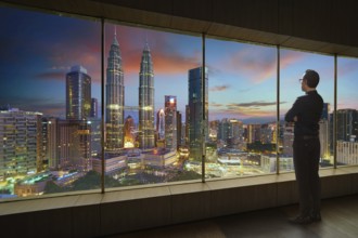 Businessman looking and thinking front of a window office with modern city skyline . Evening scene