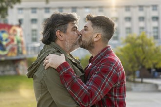 A married gay couple kissing each outdoors