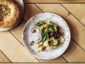 Authentic shot of georgian style salad with red beans, potatoes, salted cucumber on rustic wooden
