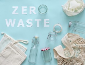 Zero waste concept. Textile eco bags, glass jar and bottle on blue background with Zero Waste white