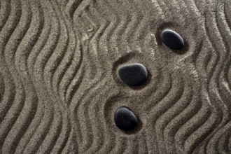 Drawings on light gray sand and black stones in a small Zen garden