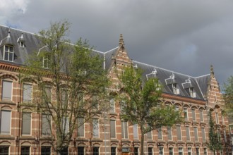 Historic buildings with gables and trees, cloudy sky, Amsterdam, Netherlands