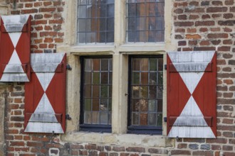 Two windows with red and white painted shutters in a brick wall, Raesfeld, Münsterland, Germany