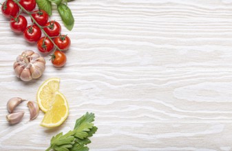 Healthy food ingredients composition with fresh cherry tomatoes, herbs, garlic cloves, lemon wedges