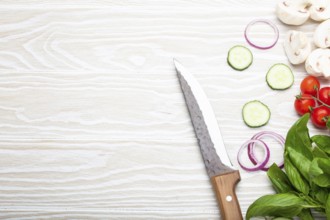 Food cooking background: fresh ingredients with kitchen knife, basil, cherry tomatoes, mushrooms,