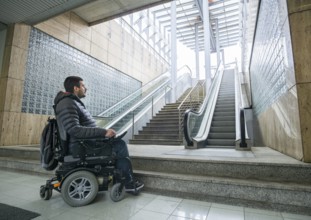 Rear View Of A Disabled Man On Wheelchair In Front Of Staircase