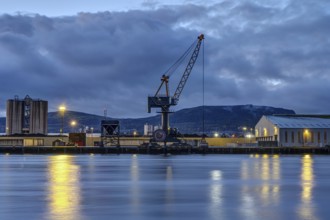 A loading crane and warehouses in Belfast harbour at dusk