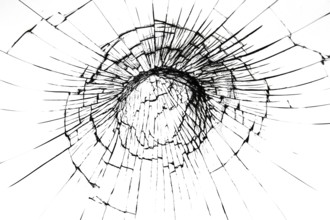 A crack on a broken glass mirror on a black background lines fragments bullet hole