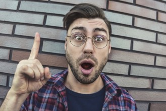 Great idea! Handsome man keeping finger pointed upwards, showing something above his head, making