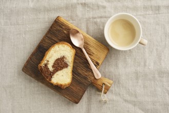 Slice of marble cake on a rustic wooden board with a cup of coffee