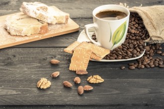 Healthy snack with slices of pound cake, biscuits, almonds, walnuts and a cup of coffee on a plate