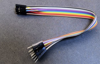 Rainbow jumper wires with pin connectors placed on a blue-toned surface