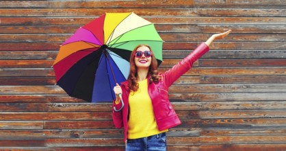 Autumn portrait of happy smiling young woman holding colorful umbrella wearing red jacket, heart