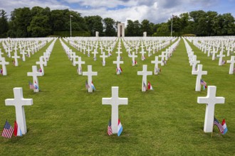 White crosses of an American military cemetery on a green lawn, lined with flags, Luxembourg