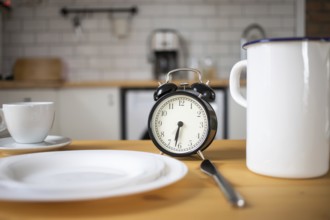 Intermittent fasting concept alarm clock on kitchen table