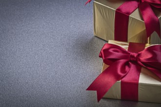 Present boxes in glittery paper on grey background horizontal view holidays concept