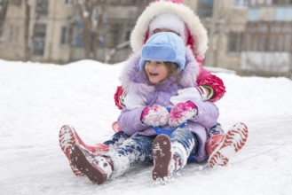 Two girls having fun rolling down the ice slide