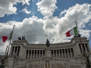 Monumental building with two Italian flags and equestrian statue under a cloudy sky, Rome, Italy