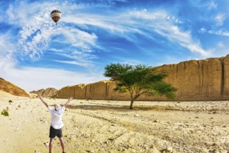 The huge multi-colored balloon flies over desert near the seaside resort of Eilat. The tourist in