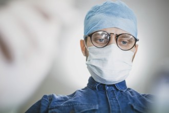 Surgeon wearing a blue cap and mask, focused on performing a medical task