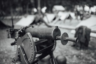 A heavy machine gun from I Word War with a military camp in the background