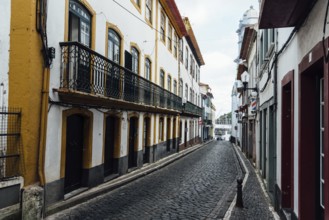 Angra do Heroismo, Portugal, July 1, 2022: Street with Traditional colonial houses painted in