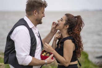 Man giving his girlfriend chocolate in the mouth on a beach