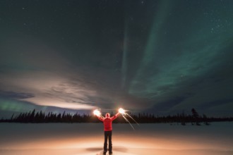 Man with burning sparklers and Northern Lights (Aurora borealis), Muddus National Park, Laponia