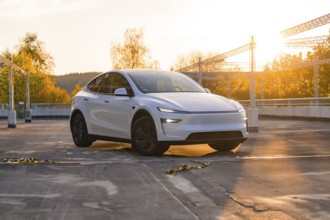 A white car in a car park with an autumnal backdrop and sunset, Tesla new Model Y Juniper, Nagold,