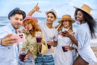 Group of cheerful young multi ethnic friends in summer clothes taking selfie with smartphone and