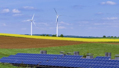 Landscape of the Swabian Alb in spring with rape field and wind turbines. In front of it a building
