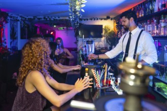 Bartender mixing vibrant cocktails in a trendy nightclub, serving young women at the bustling bar
