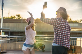 Two friends sharing a joyful high five after an exhilarating longboarding session, basking in the