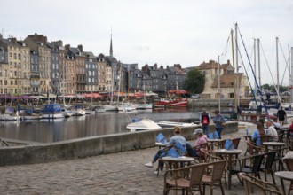 Honfleur, Normandy, France - Boats on the Quai Sainte-Catherine and people in the street café in