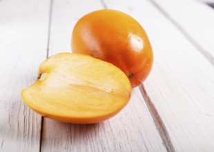 Ripe orange persimmon on white wooden background, with copy space, top view
