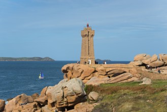Lighthouse overlooking the rocky coast with sailing boat on the horizon, Phare de Men Ruz,