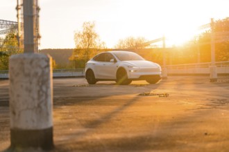 White car at sunset in an urban car park with light columns, Tesla new Model Y Juniper, Nagold,