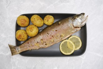 Overhead view of plate with whole baked rainbow trout and baby potatoes