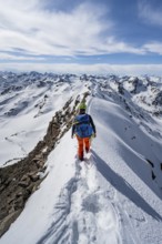 Mountaineer on a narrow mountain ridge in winter, summit of Piz Grialetsch, view of mountain